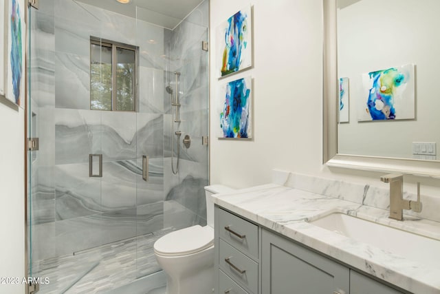 bathroom with a shower with door, toilet, and vanity