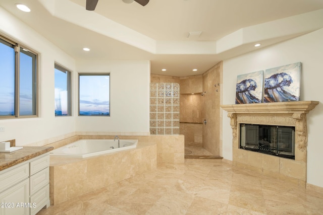 bathroom featuring tile floors, ceiling fan, vanity, a tiled fireplace, and shower with separate bathtub