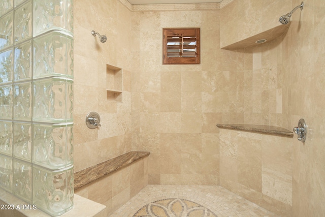 bathroom with ornamental molding and tiled shower