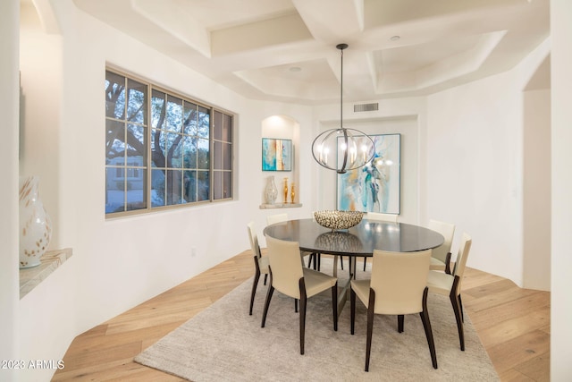 dining room featuring an inviting chandelier, light wood-type flooring, and coffered ceiling