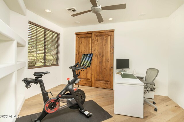 exercise room with ceiling fan and light wood-type flooring