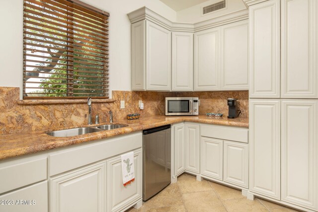 kitchen with light tile flooring, appliances with stainless steel finishes, sink, light stone counters, and tasteful backsplash