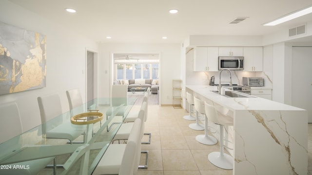 kitchen featuring recessed lighting, stainless steel microwave, visible vents, white cabinets, and light tile patterned flooring