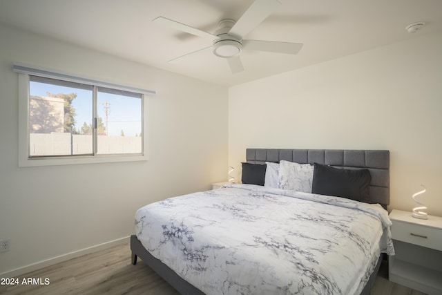 bedroom with ceiling fan, wood finished floors, and baseboards