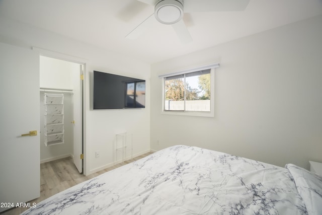 bedroom featuring baseboards, ceiling fan, wood finished floors, a spacious closet, and a closet