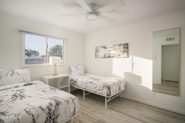 bedroom featuring a ceiling fan, light wood-type flooring, visible vents, and baseboards