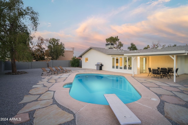 back of house at dusk with a fenced backyard, a fenced in pool, and a patio