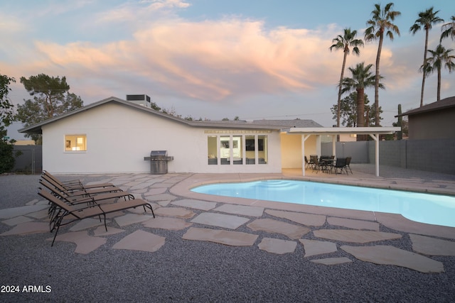 view of swimming pool with a patio, central AC, area for grilling, fence, and a fenced in pool