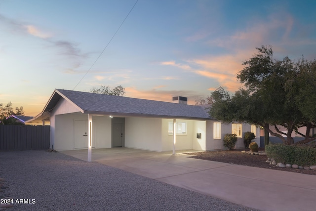 ranch-style home with roof with shingles, a chimney, fence, and stucco siding