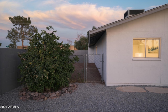 view of property exterior featuring a gate, fence, and central AC unit