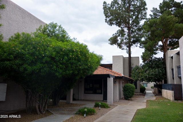 exterior space featuring a tiled roof and stucco siding
