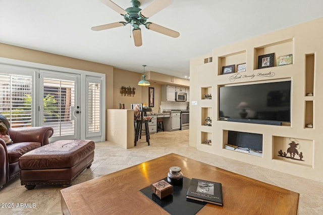 living room with built in features and ceiling fan