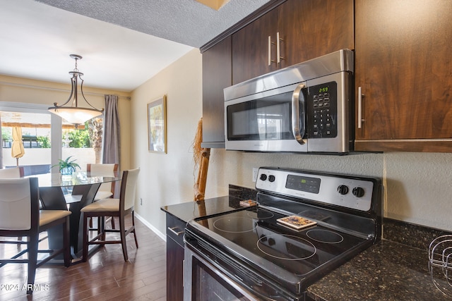 kitchen featuring dark stone counters, dark hardwood / wood-style flooring, appliances with stainless steel finishes, pendant lighting, and dark brown cabinetry