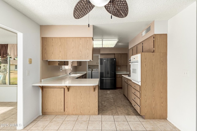 kitchen with separate washer and dryer, black fridge, kitchen peninsula, ceiling fan, and a breakfast bar area