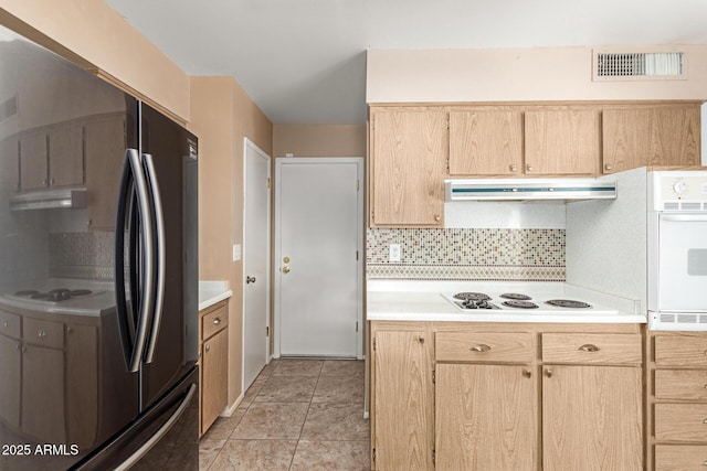 kitchen with light brown cabinets, backsplash, light tile patterned floors, and white appliances