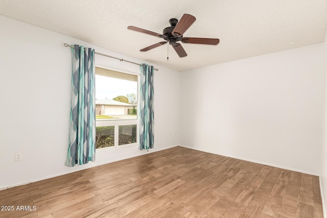 empty room with light hardwood / wood-style floors, a wealth of natural light, and ceiling fan