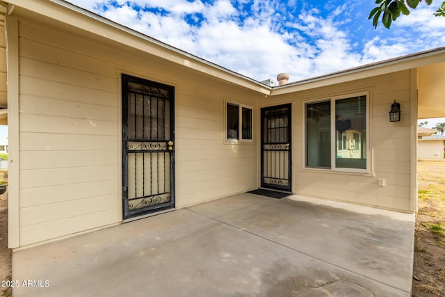 view of exterior entry with a patio