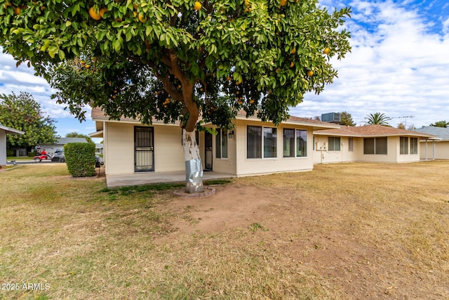 back of house featuring cooling unit, a yard, and a patio