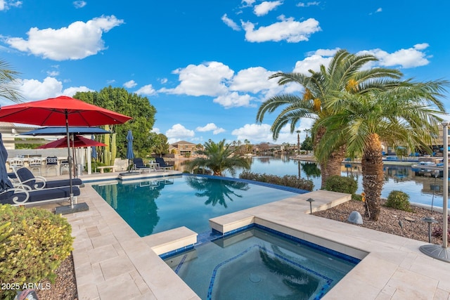 view of swimming pool featuring an in ground hot tub, a water view, and a patio area