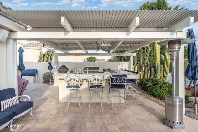 view of patio / terrace featuring ceiling fan, area for grilling, and exterior bar