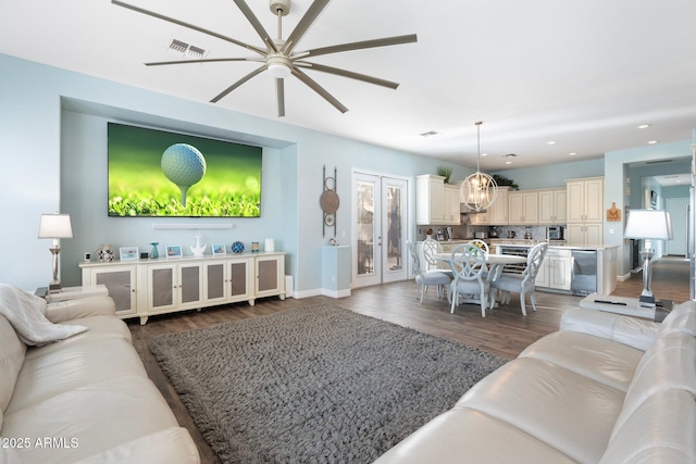 living room featuring dark wood-type flooring and ceiling fan with notable chandelier