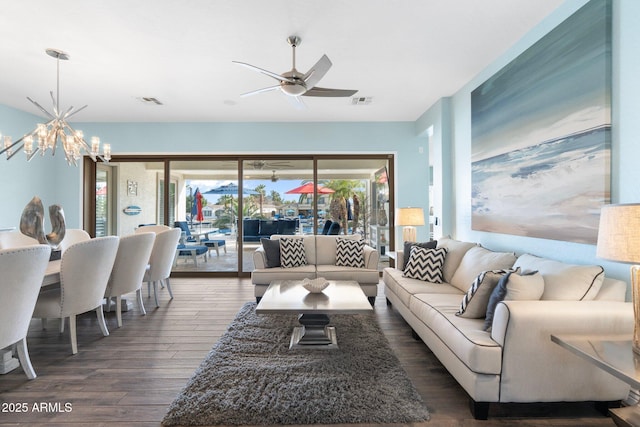 living room with ceiling fan with notable chandelier and dark wood-type flooring