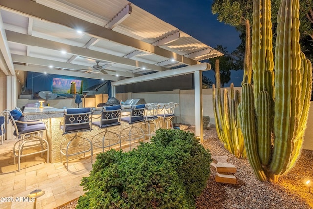 patio at twilight with grilling area, a pergola, and an outdoor bar