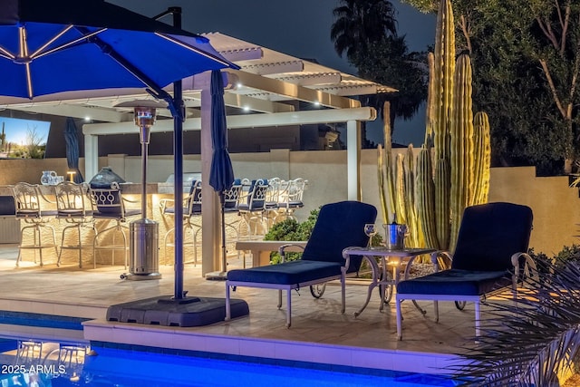 patio at twilight featuring exterior bar and an outdoor kitchen