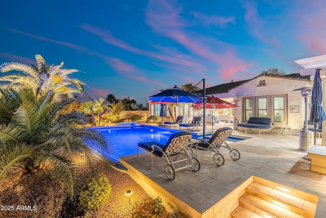 pool at dusk featuring a patio area