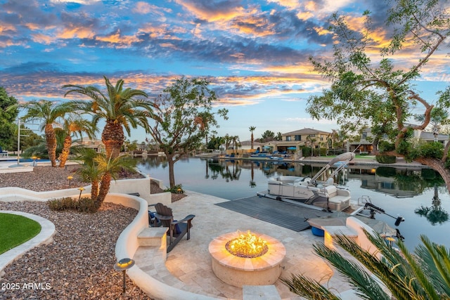 view of property's community with a water view, a boat dock, and an outdoor fire pit