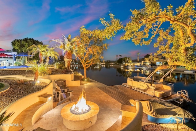 exterior space with a water view, a patio area, and a fire pit