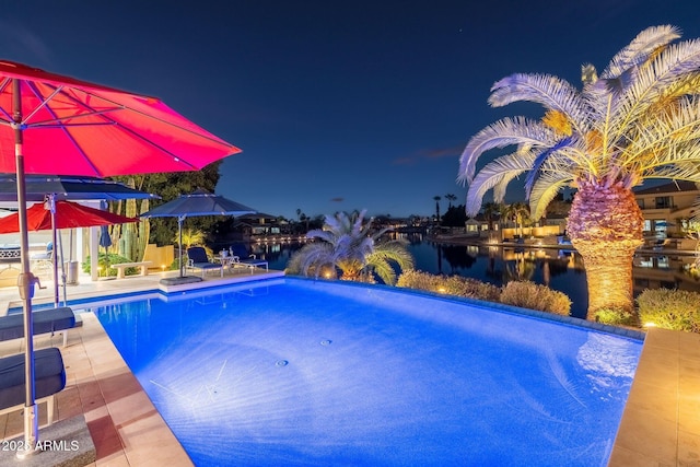 pool at night featuring a water view