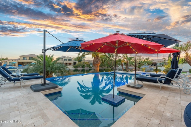 pool at dusk with a patio area