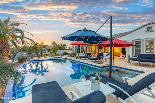 pool at dusk featuring a patio area