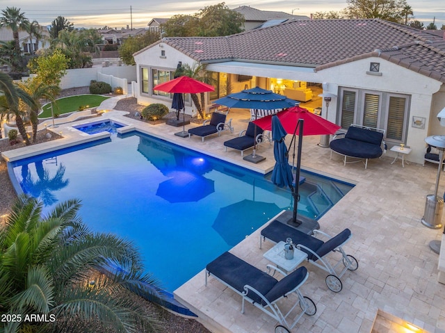 pool at dusk with an outdoor structure, a patio, and an in ground hot tub