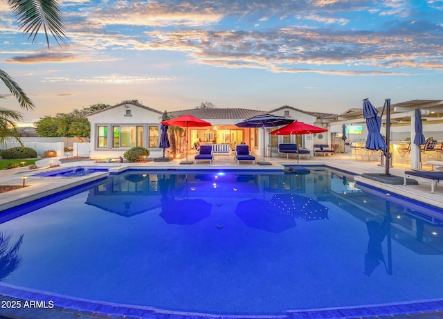 pool at dusk with a patio and an outbuilding