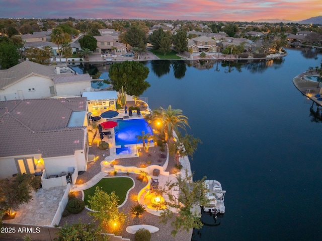 aerial view at dusk featuring a water view