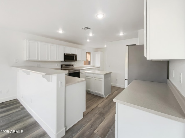 kitchen featuring wood finished floors, visible vents, a peninsula, appliances with stainless steel finishes, and white cabinetry