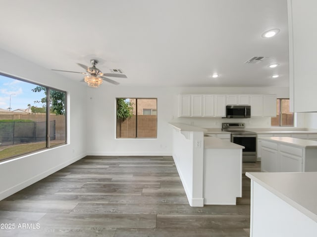 kitchen with visible vents, white cabinetry, stainless steel appliances, a peninsula, and light countertops