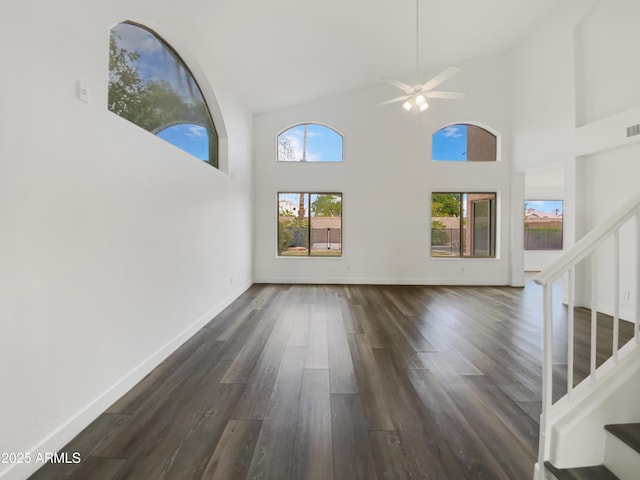 unfurnished living room featuring dark wood-style floors, stairway, high vaulted ceiling, and baseboards