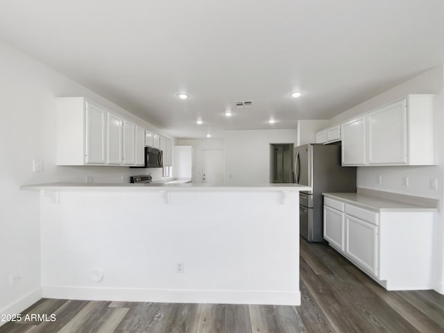 kitchen featuring a kitchen breakfast bar, a peninsula, white cabinets, and freestanding refrigerator