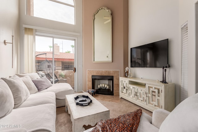 carpeted living room featuring a fireplace and a towering ceiling