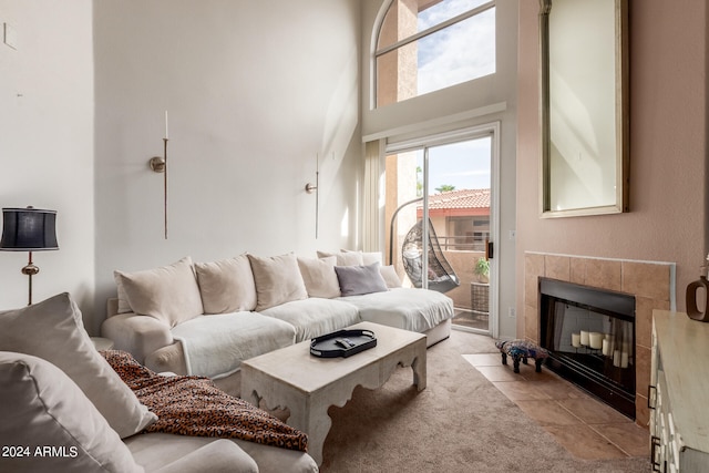 living room with light tile patterned floors, a towering ceiling, and a tiled fireplace