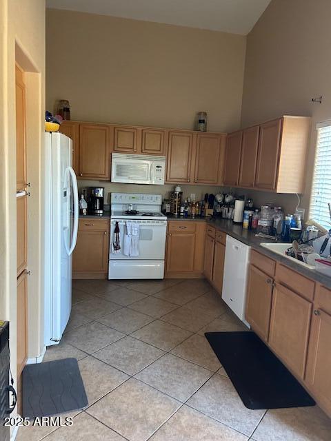 kitchen with white appliances, light tile patterned floors, light brown cabinets, high vaulted ceiling, and a sink