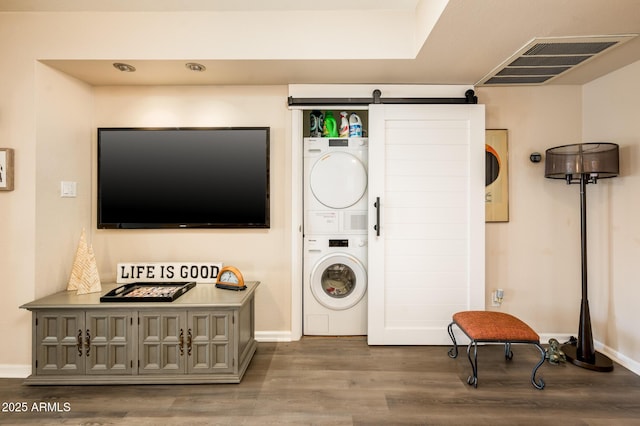 5209 N 78th St, Scottsdale, AZ 85250 - laundry area featuring stacked washer and clothes dryer, wood finished floors, a barn door, and baseboards