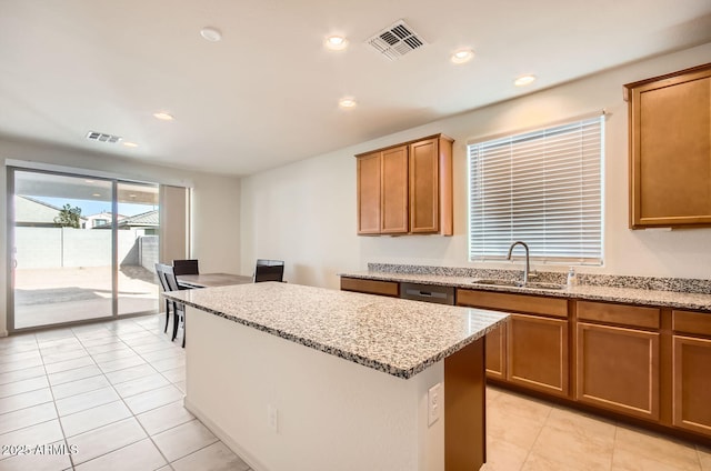 kitchen with a center island, light stone counters, light tile patterned floors, and sink