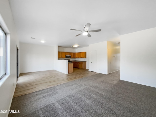 unfurnished living room featuring light colored carpet and ceiling fan