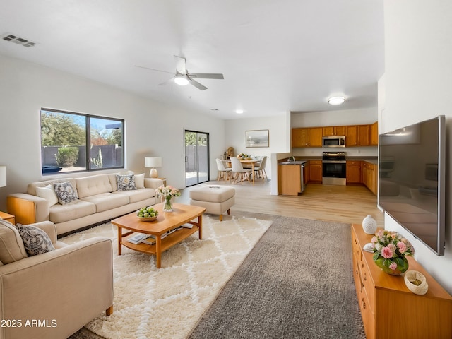 living room featuring sink, ceiling fan, a wealth of natural light, and light hardwood / wood-style flooring