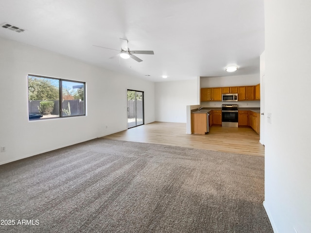 unfurnished living room with ceiling fan, sink, and light colored carpet