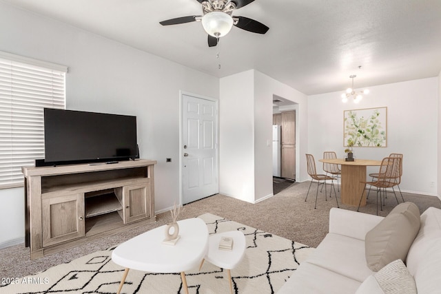 carpeted living room with ceiling fan with notable chandelier